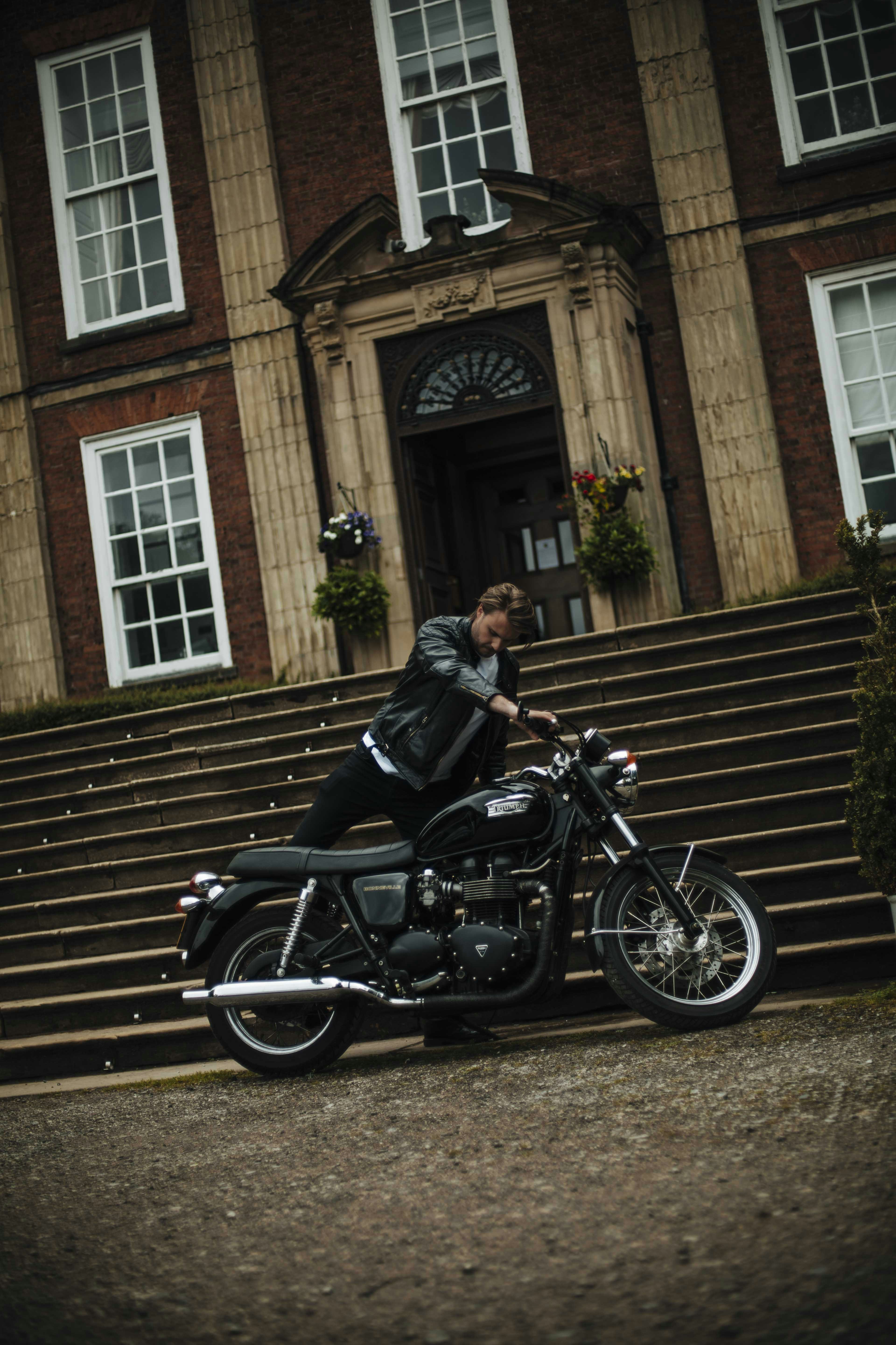 uomo in giacca di pelle nera in sella a moto nera
