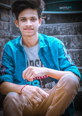 A casual scene featuring a student in a graphic t-shirt and light wash jeans, sitting on campus steps with a relaxed smile.