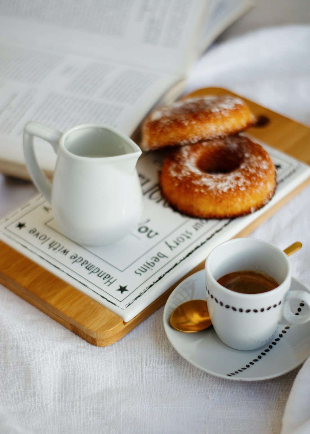 white ceramic mug beside brown doughnut on white ceramic plate