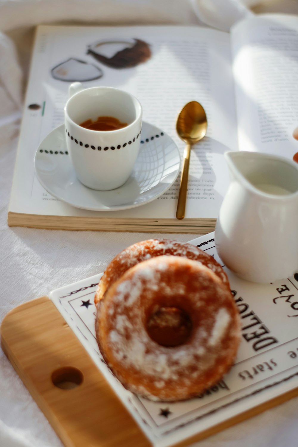 white ceramic mug on white ceramic plate beside stainless steel spoon