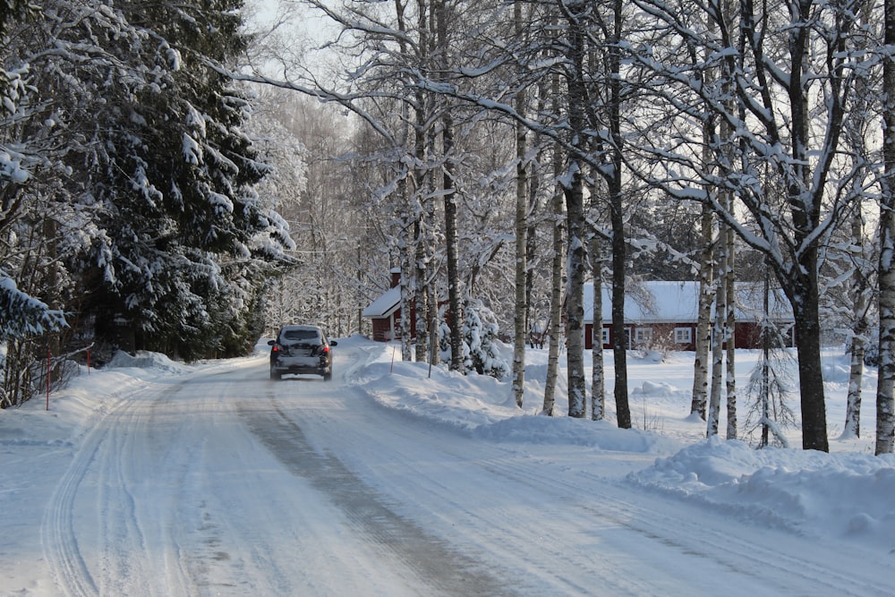 black car on road covered with snow during daytime