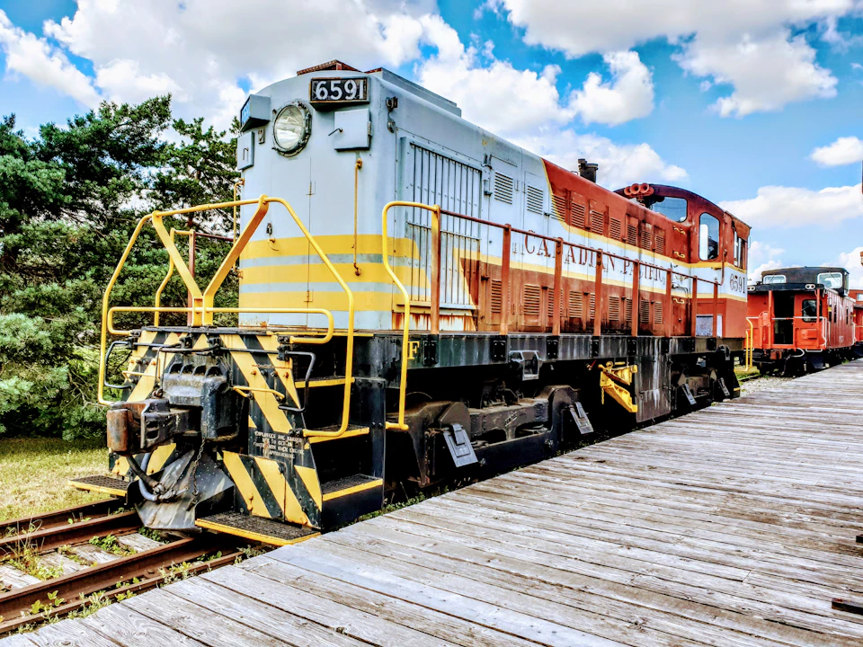 Red and white train engine 5599 parked on wooden bridge with metal railing