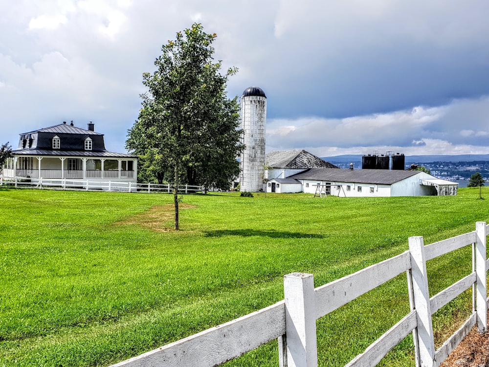 white and gray house near green grass field and trees under white clouds during daytime