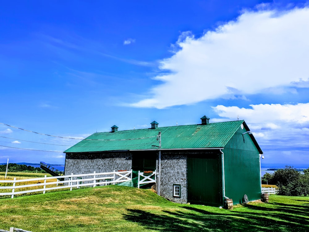 casa de madeira verde no campo de grama verde sob o céu azul durante o dia