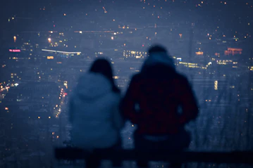 man and woman sitting on bench during night time