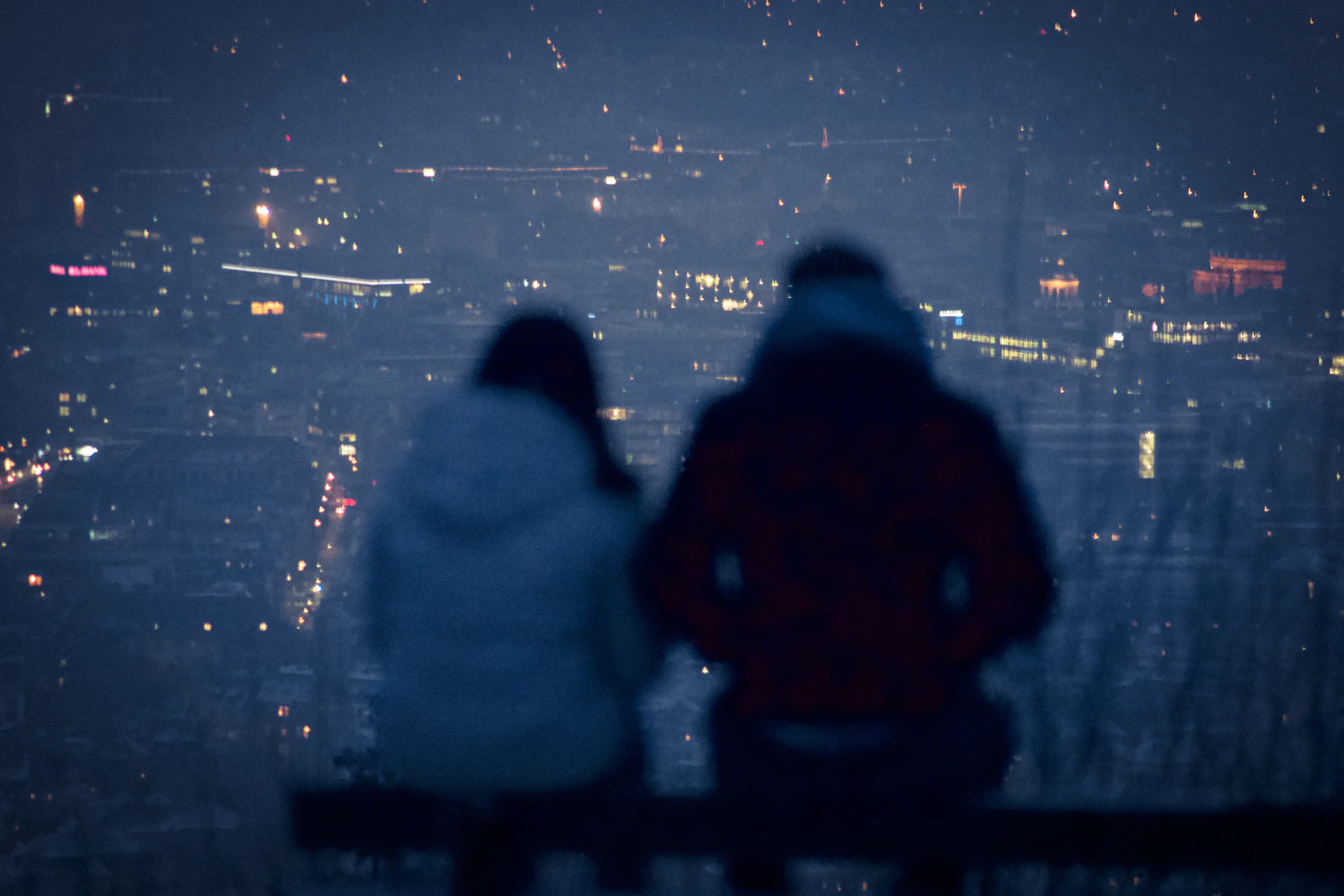 A man and woman sitting together on a bench in the evening, talking