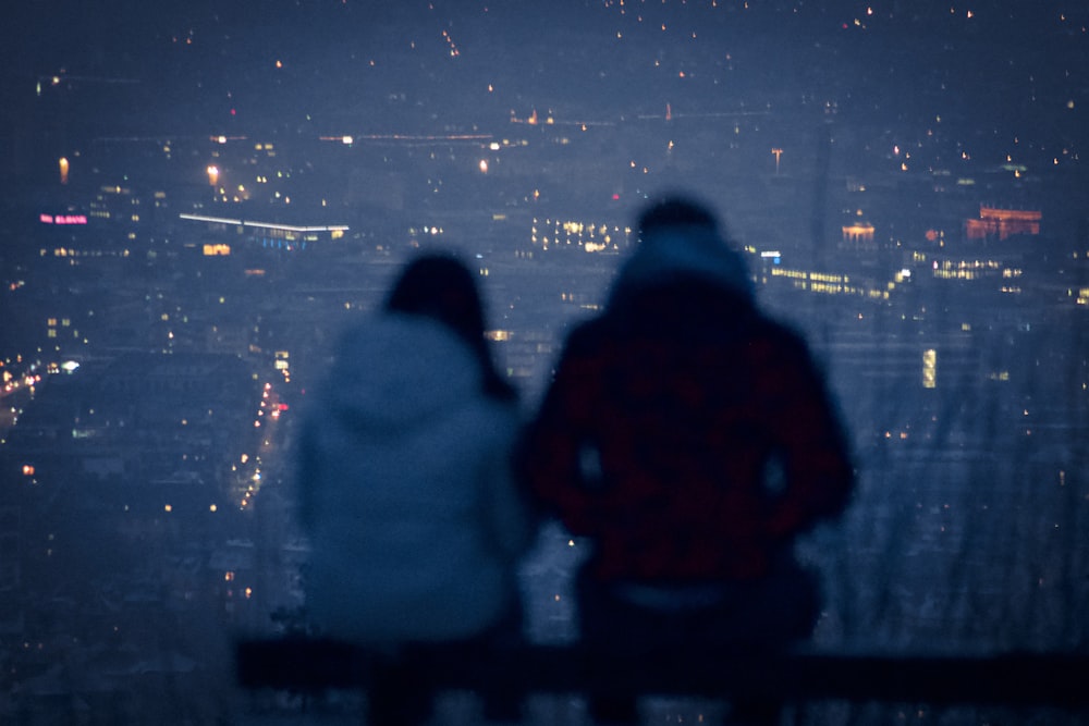 man and woman sitting on bench during night time