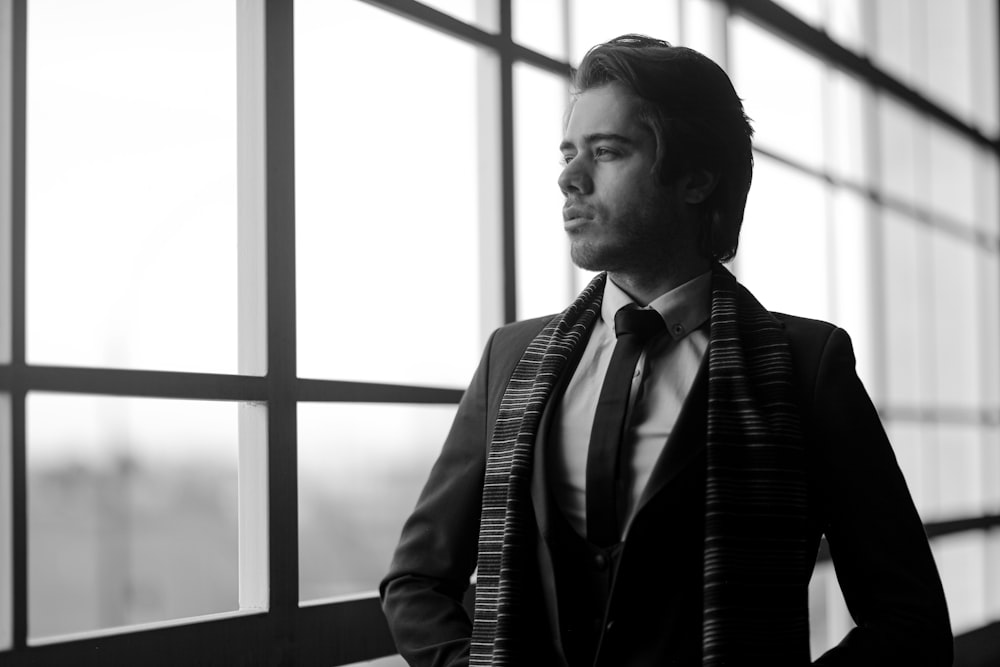 man in black and white suit standing near window