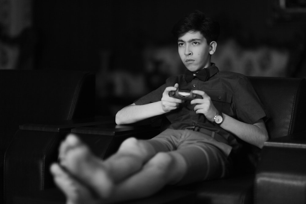 man in black button up shirt and black shorts sitting on chair