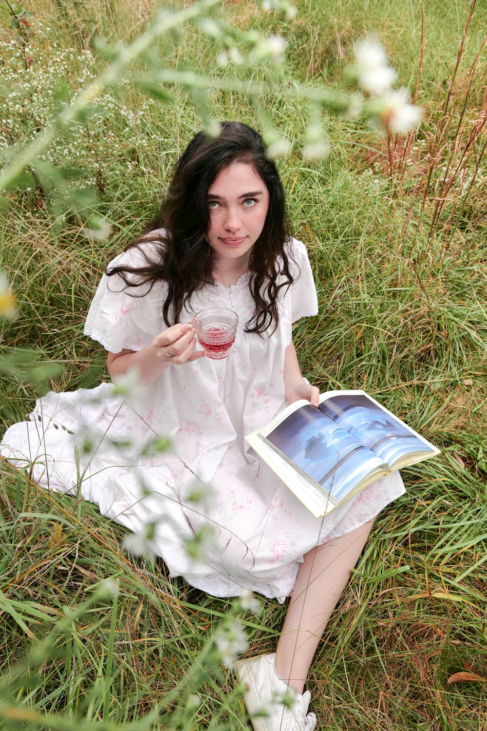 femme en robe blanche assise sur le champ d’herbe verte