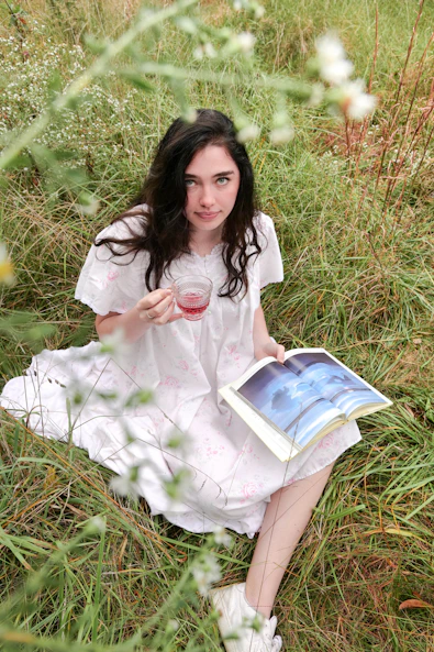 woman in white dress sitting on green grass field