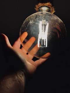 Hands holding a shining Mahakal LED bulb, showcasing its compact design