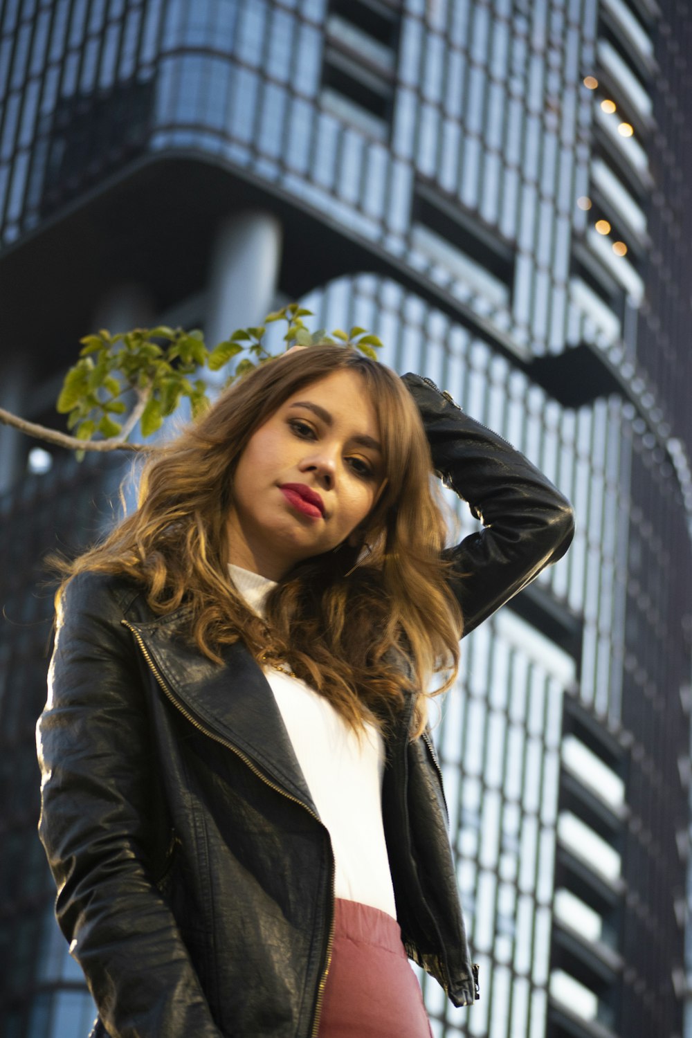 woman in black leather jacket standing near building during daytime