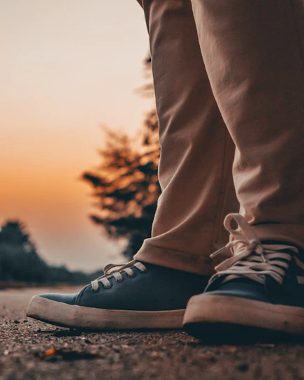 A close-up of a runner's legs wearing sleek compression knee sleeves, muscles flexed mid-stride on a sunlit trail.