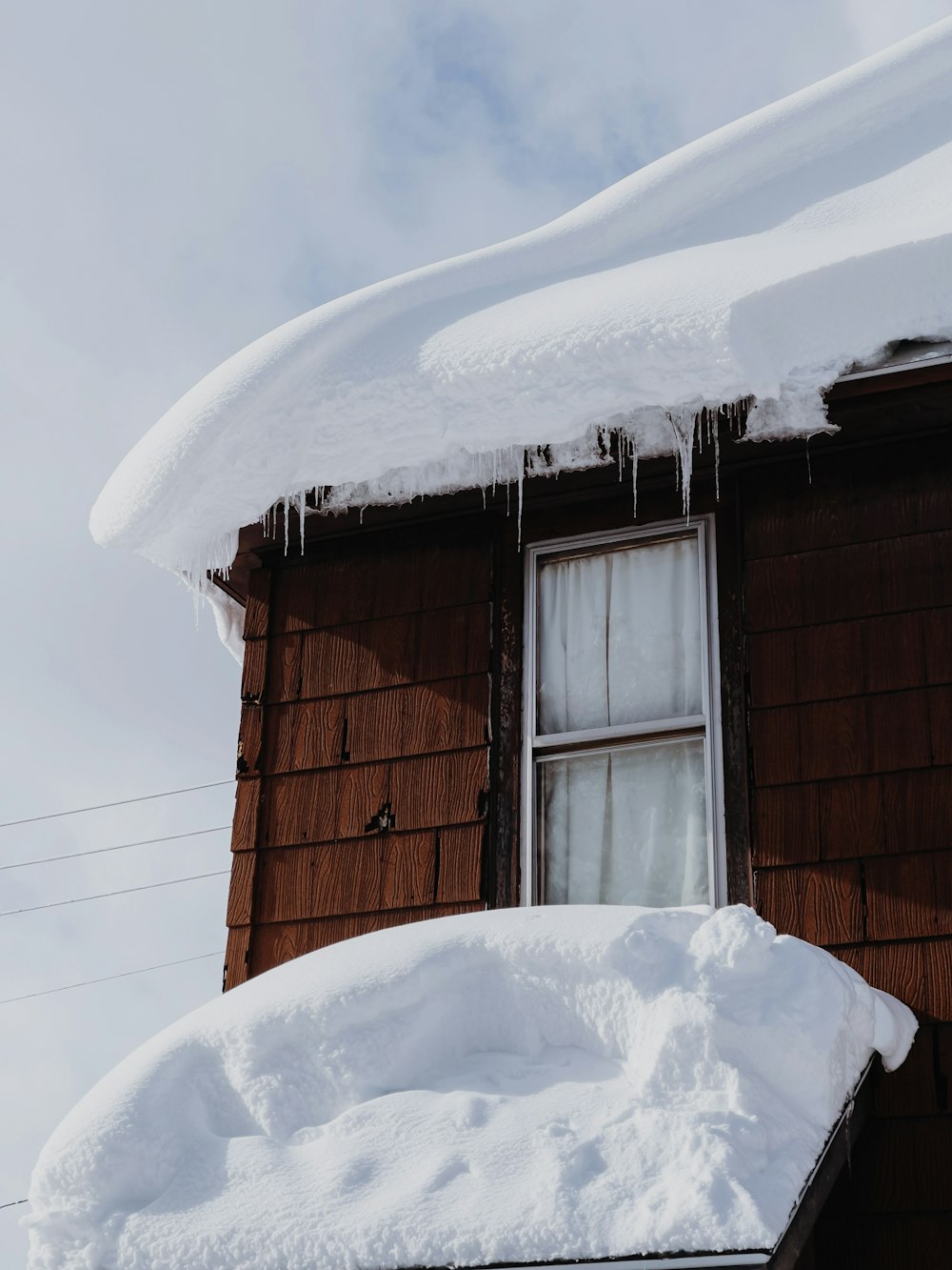 雪に覆われた茶色の木造住宅