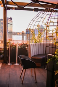 Rooftop terrace with lush plants, comfortable seating, and city views at sunset.