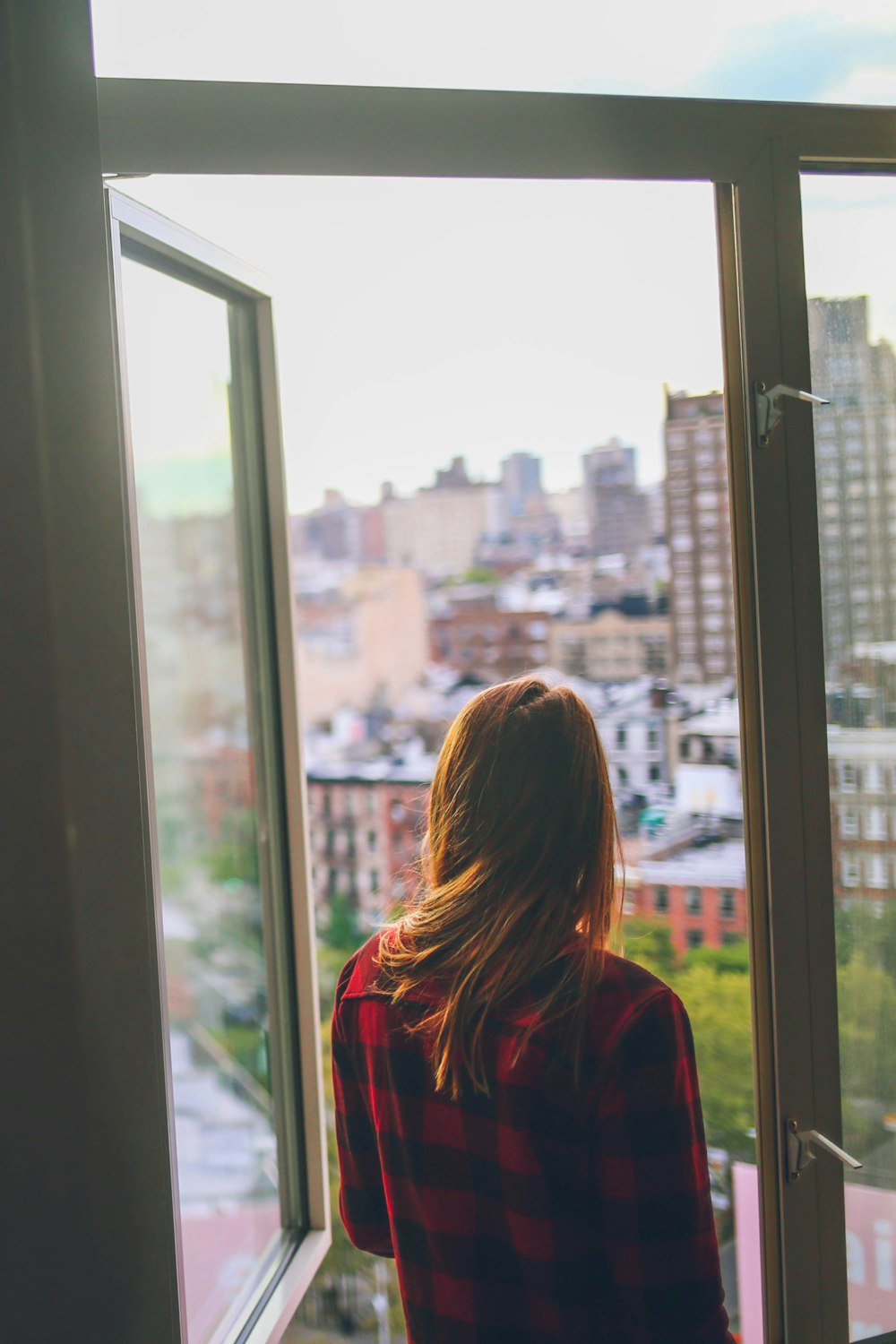 woman in red jacket looking at the city during daytime