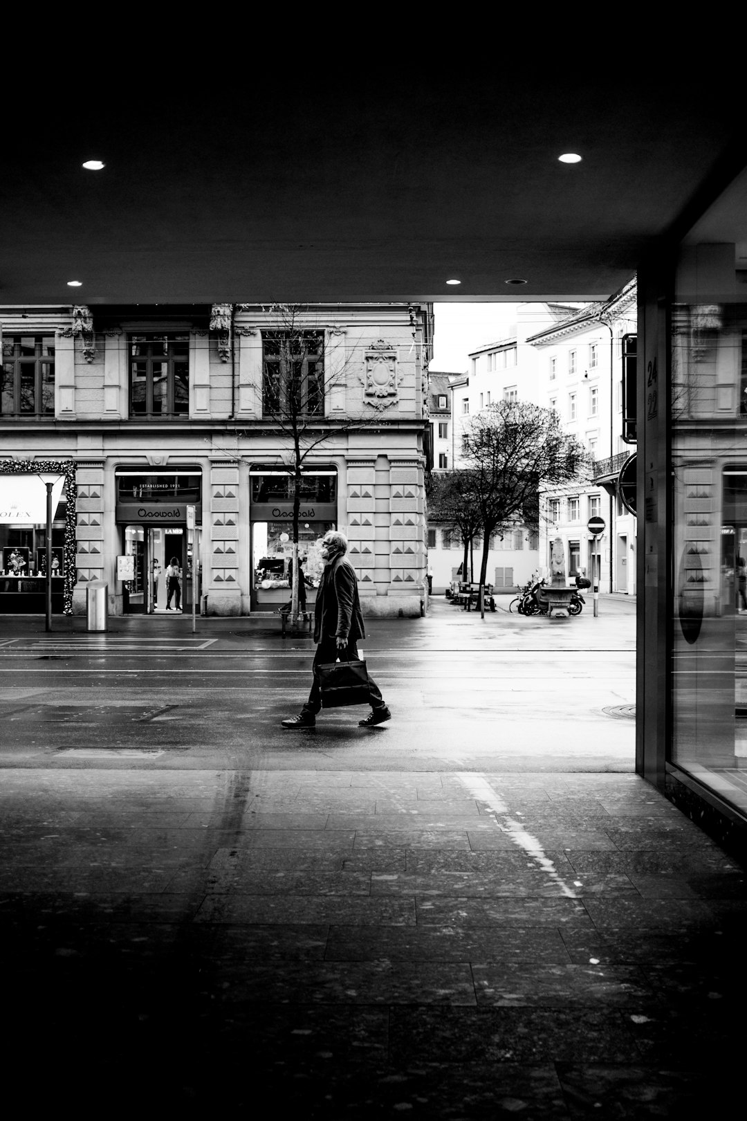 grayscale photo of woman walking on sidewalk