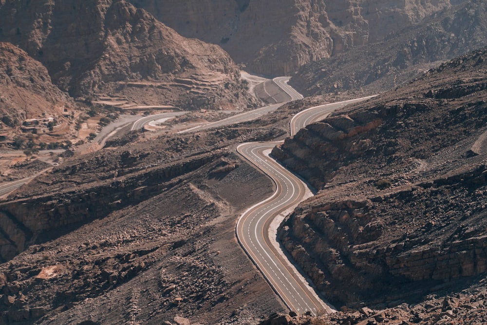 strada asfaltata grigia tra le montagne marroni durante il giorno