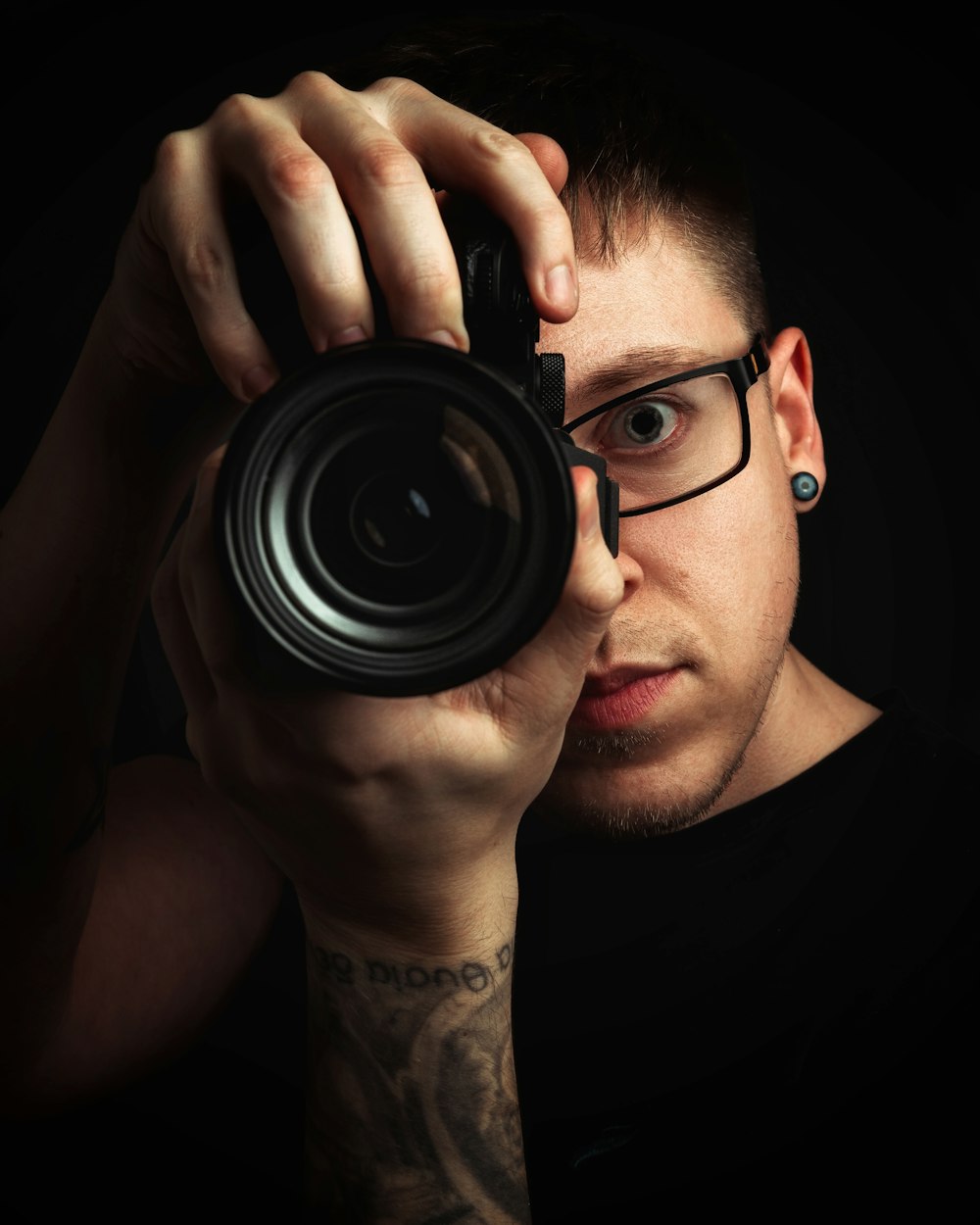 man in black shirt holding black camera lens
