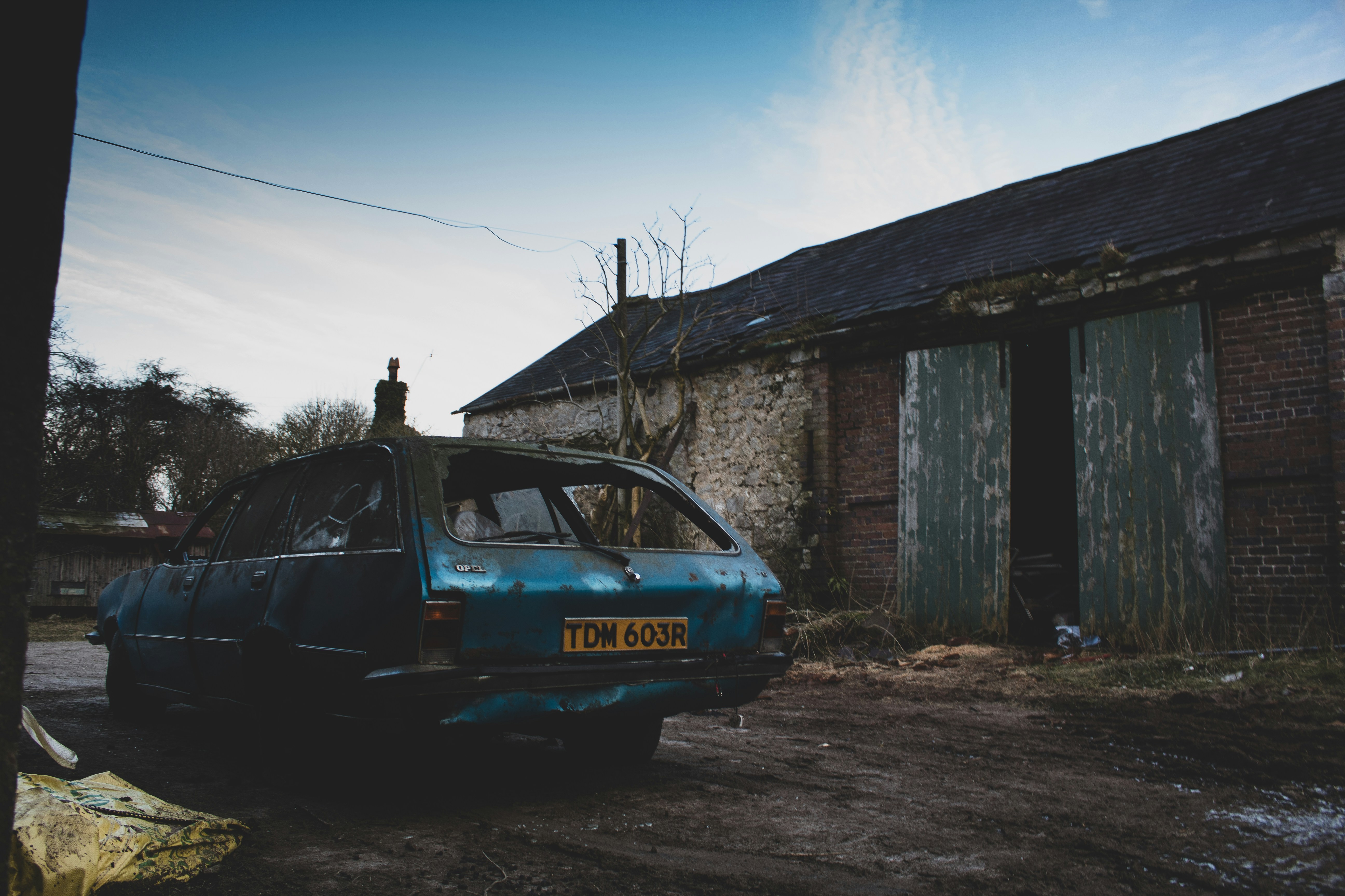 blue car parked beside brown wooden house