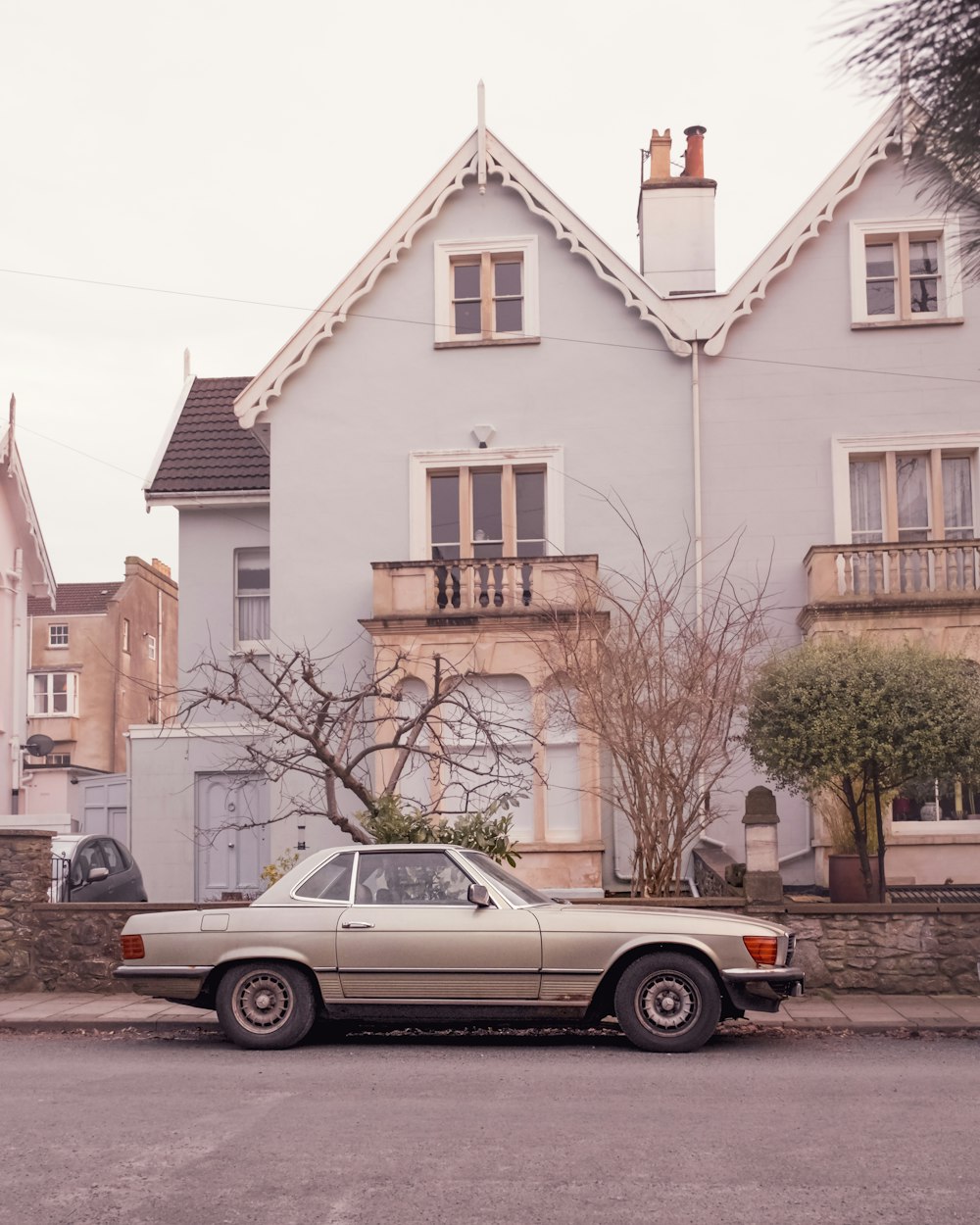 white sedan parked beside brown concrete building during daytime