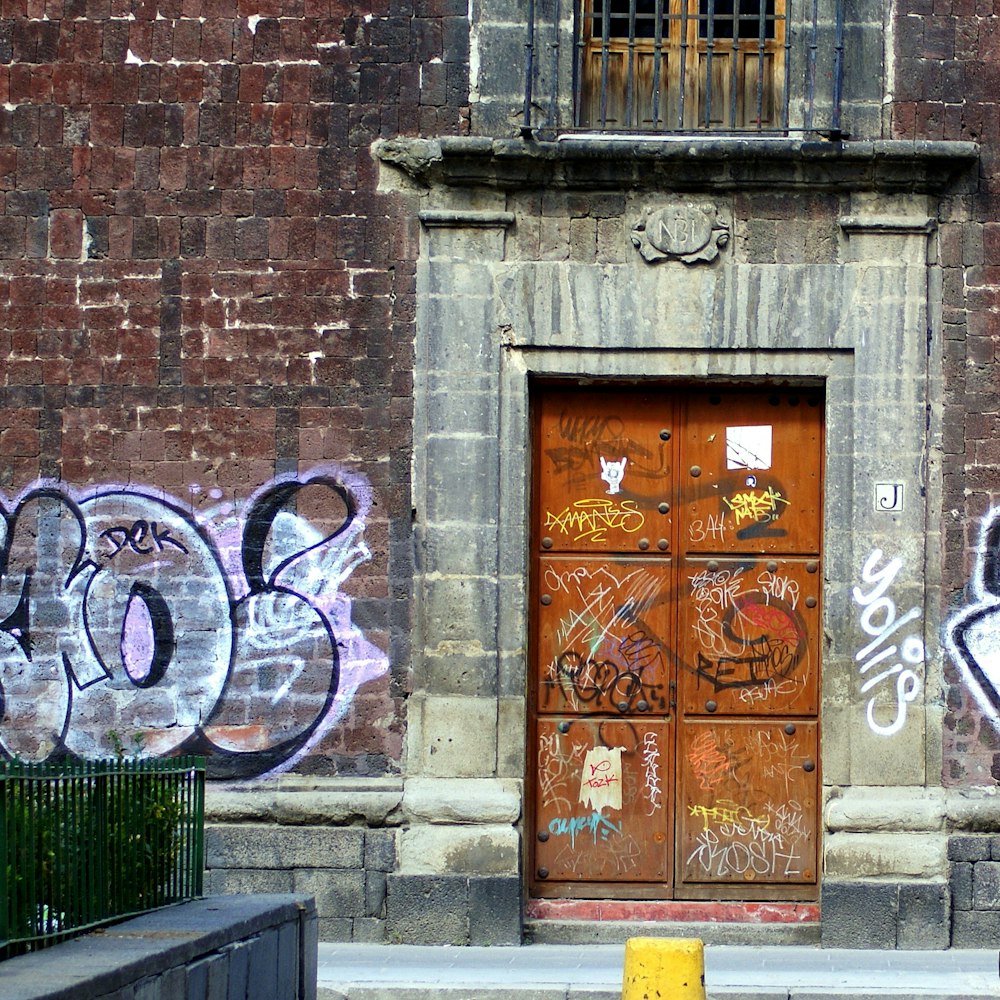 brown wooden door with white and blue graffiti