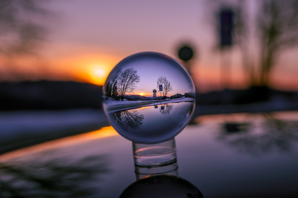 Sfera di vetro trasparente sulla strada asfaltata nera durante il tramonto