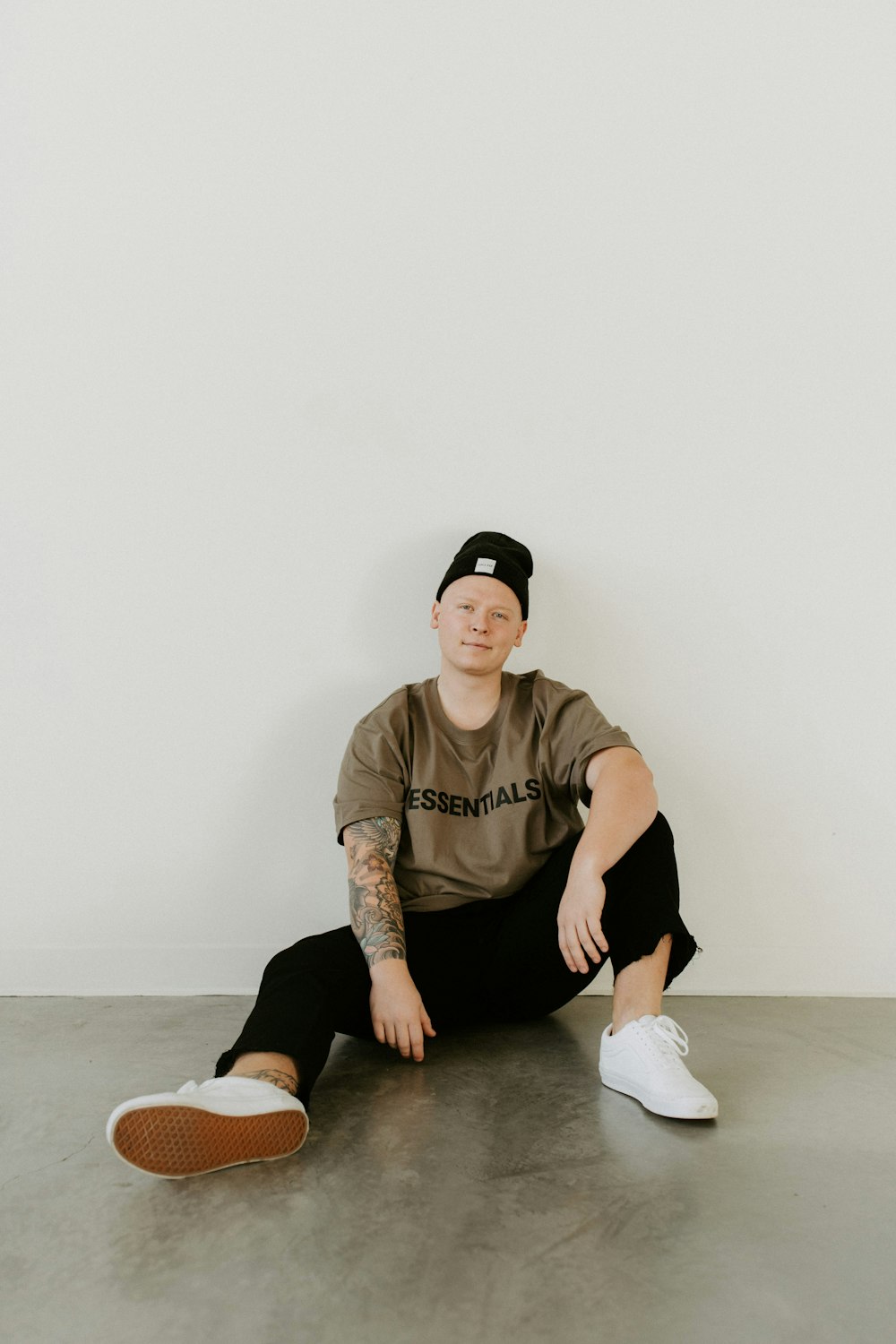 man in brown crew neck t-shirt and black pants sitting on floor