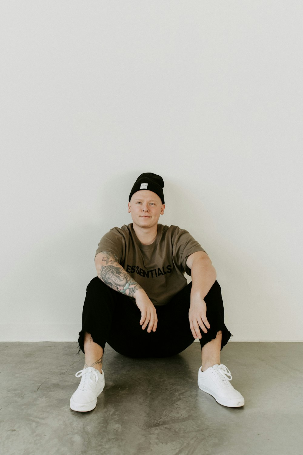 man in brown crew neck t-shirt and black pants sitting on floor