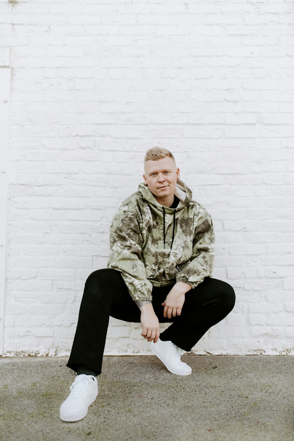 a man sitting against a white brick wall