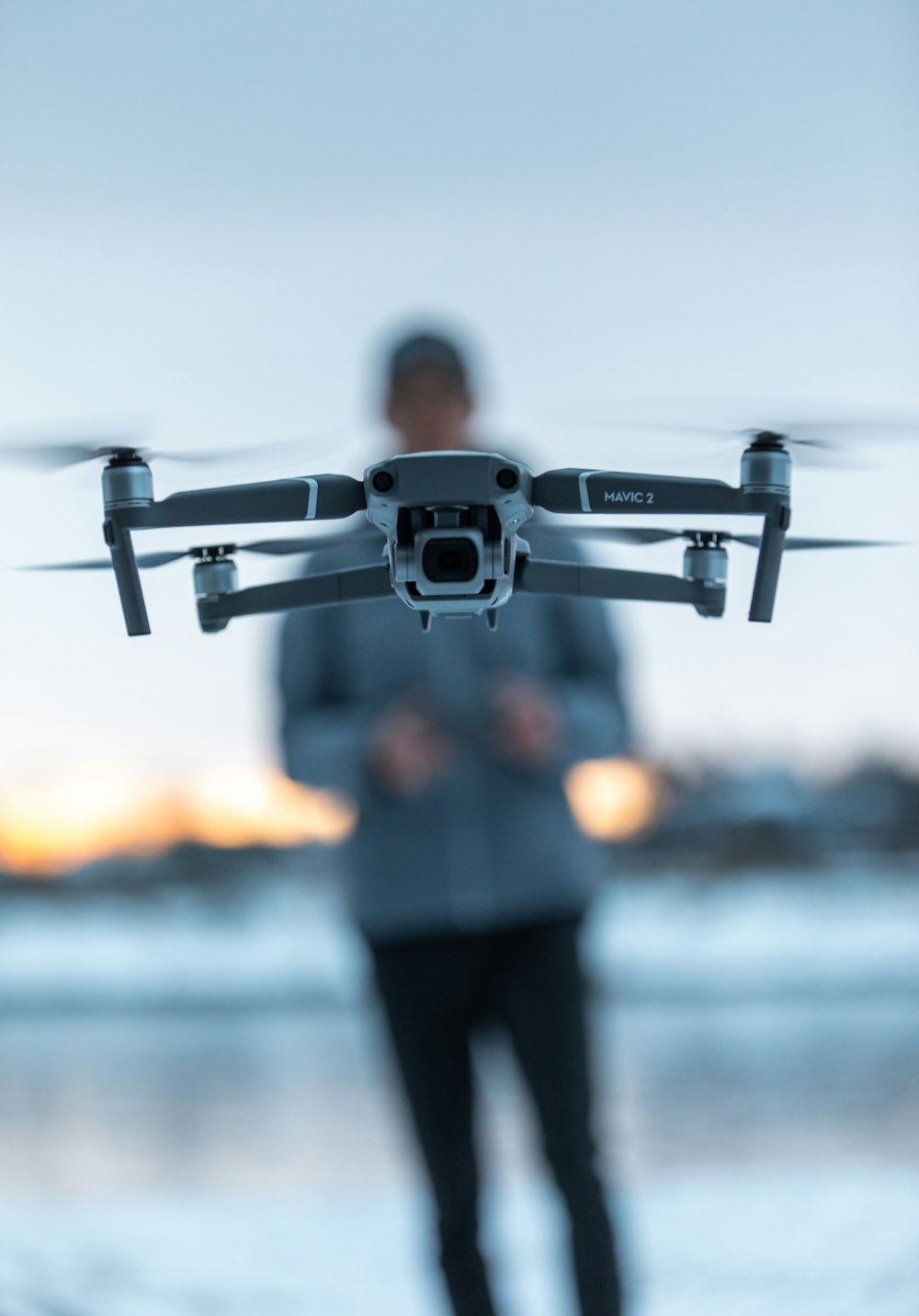 black drone flying over the man in black pants