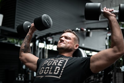 man in black crew neck t-shirt holding black and silver dumbbell determined google meet background