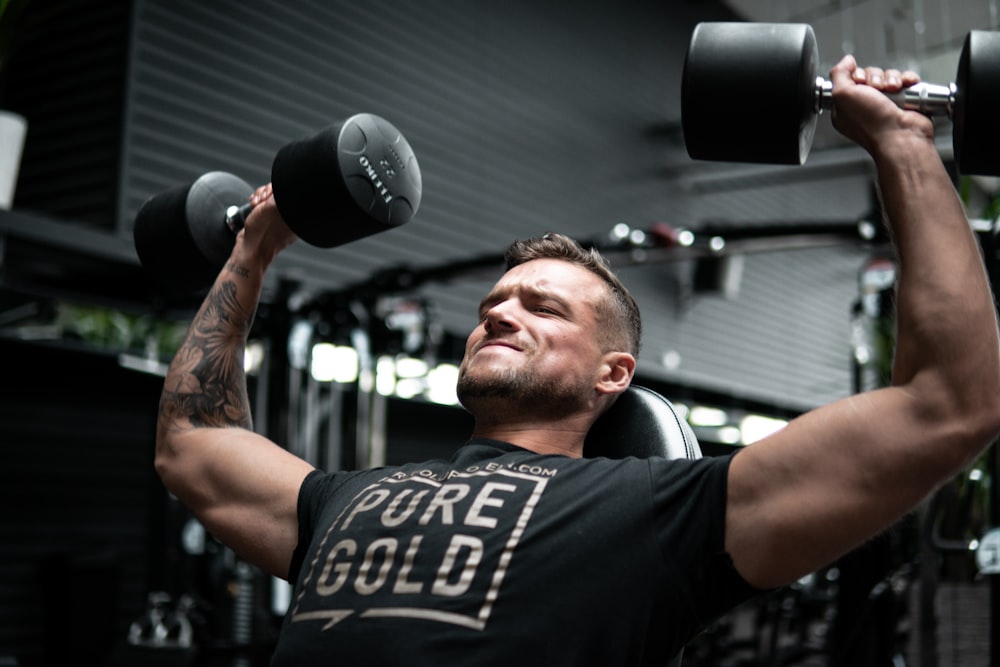 man in black crew neck t-shirt holding black and silver dumbbell