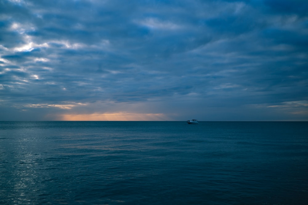 barco no mar sob o céu azul e nuvens brancas durante o dia