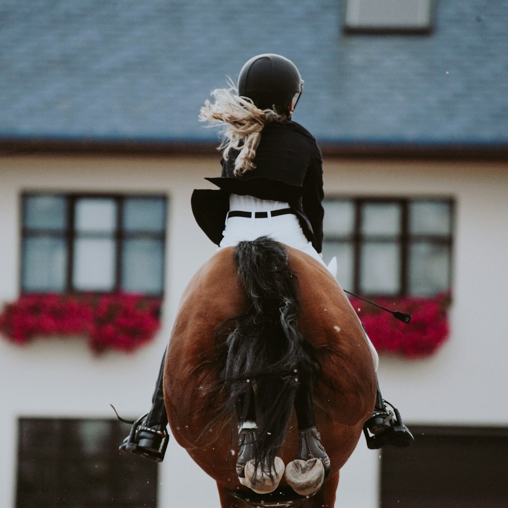 Mann in schwarz-weißer Tracht reitet auf braunem Pferd