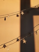 Star-shaped string lights are hanging against a wall, casting distinct shadows. The warm tone of the lighting creates a cozy and inviting atmosphere.