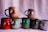 A collection of uniquely designed ceramic mugs, each featuring a raised, abstract sculpture on the side resembling human torsos. The mugs are arranged in two rows against a plain backdrop, showcasing various colors including pink, red, green, and grey.