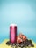 A vibrant composition with a tall pink can labeled 'Hungry Healthy Happy' surrounded by fresh fruit, including pomegranate halves, blackberries, and blueberries, set against a backdrop of light blue and lime green surfaces.