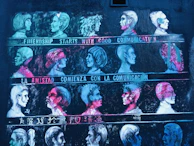 A mural features rows of stylized profile portraits in various vibrant colors. Each row is accompanied by a phrase about communication in different languages, including English, Spanish, and Chinese. The artwork uses contrast between bright neon colors and a dark background to highlight the faces.