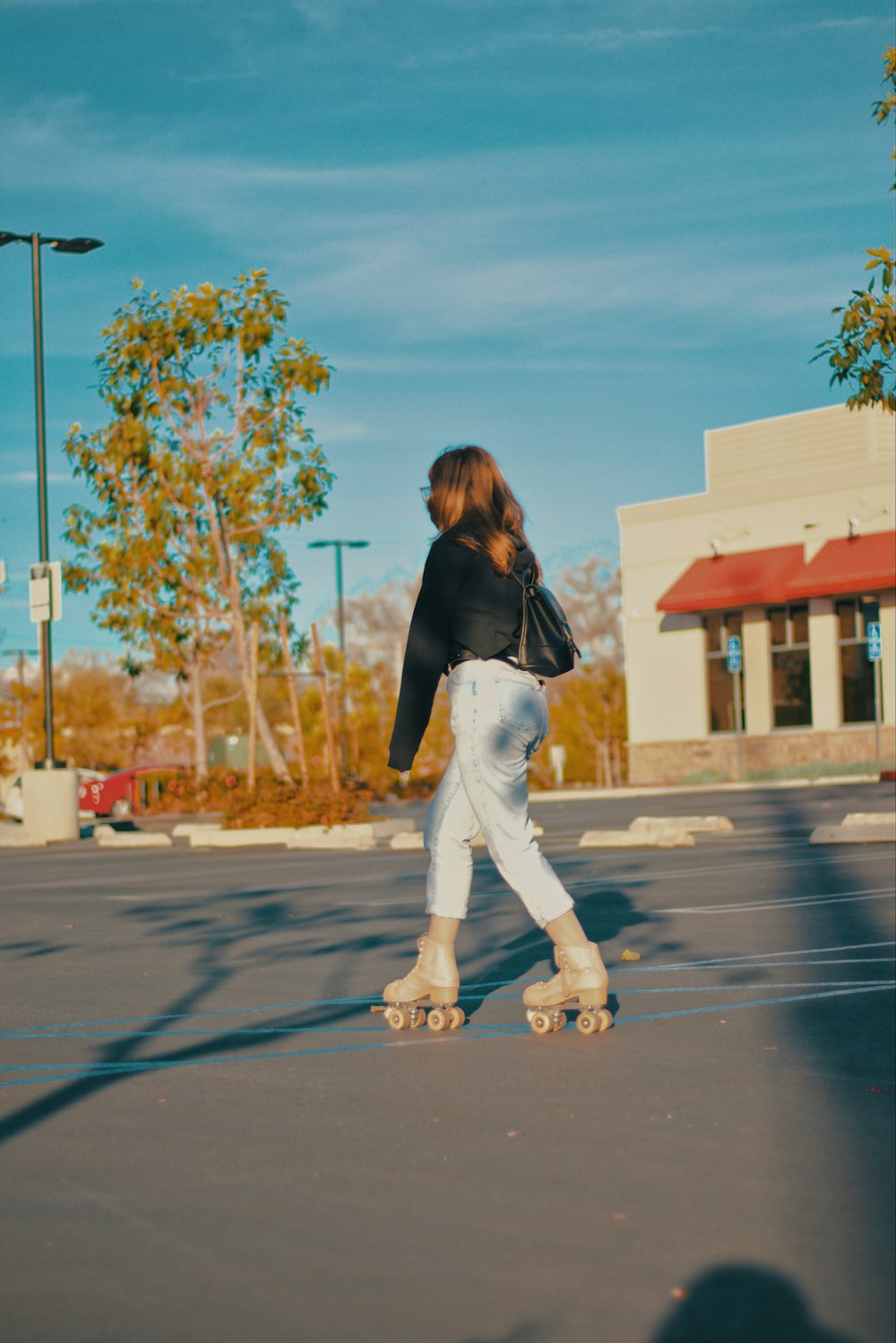 woman in black long sleeve shirt and white pants walking on street during daytime