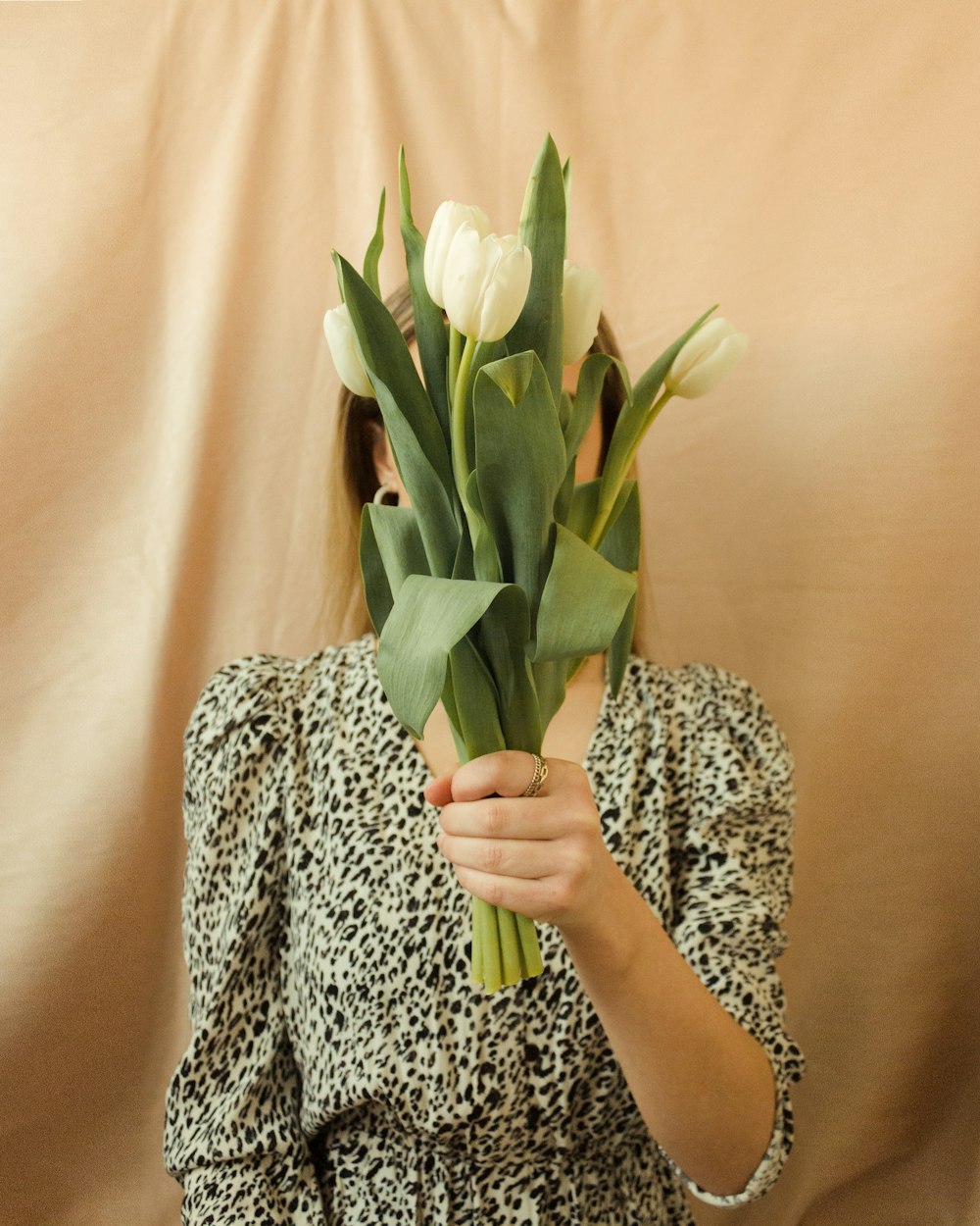 woman in gray and black long sleeve shirt holding white tulips bouquet