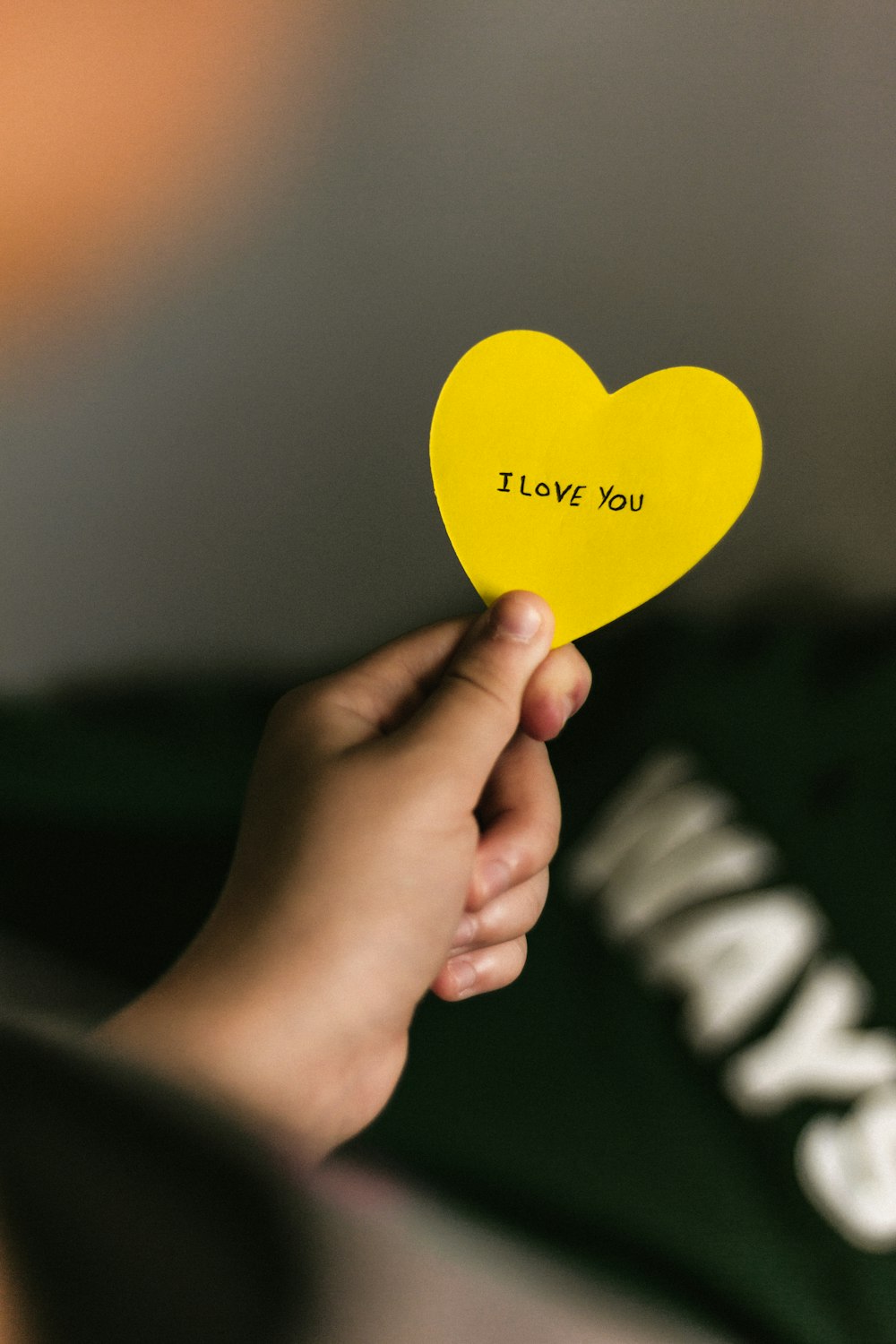 person holding yellow heart paper