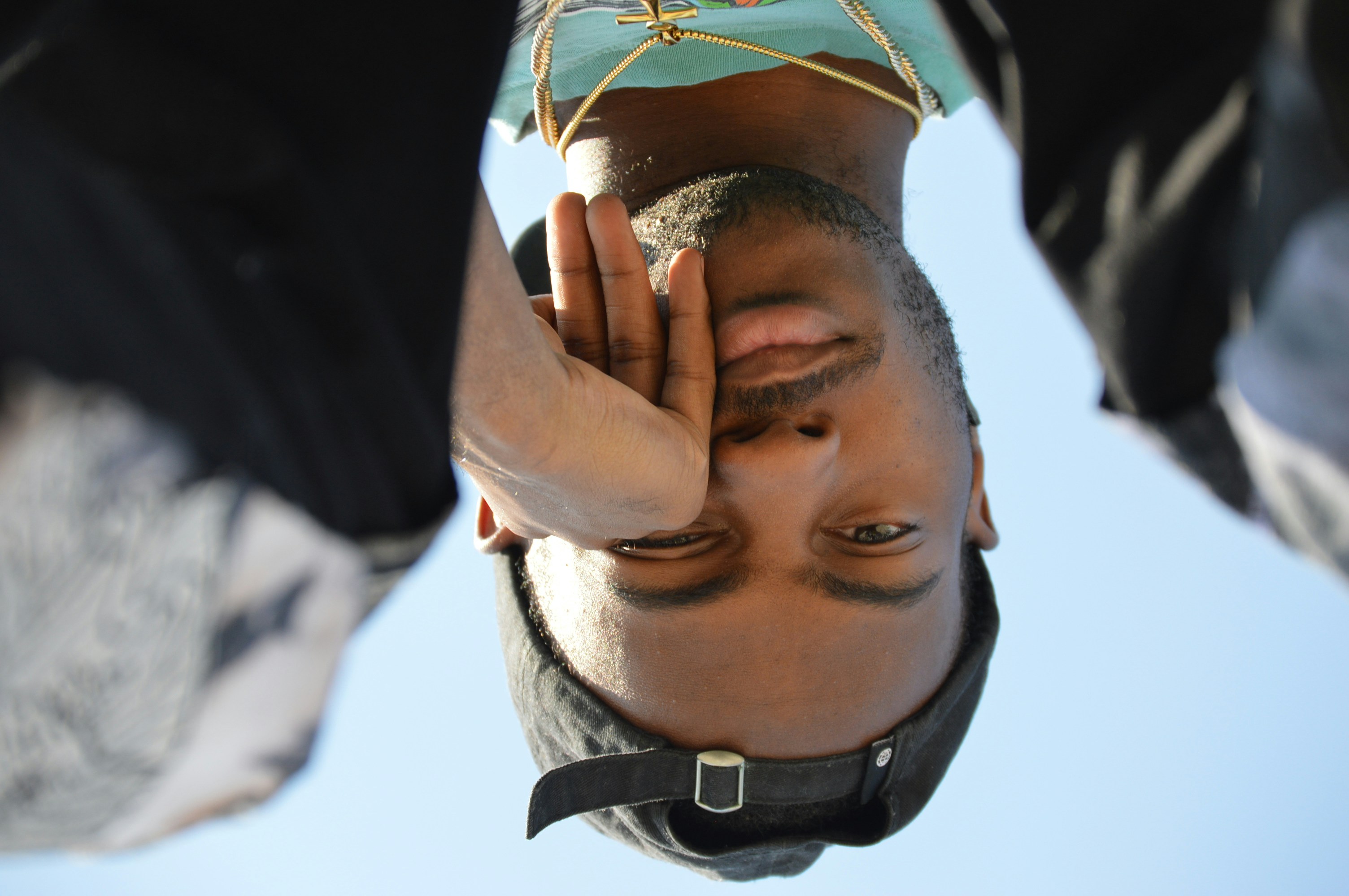 Mann in schwarzer Lederjacke bedeckt sein Gesicht mit grünen Blättern