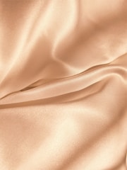 Close-up of delicate satin bonnet resting on soft fabric.