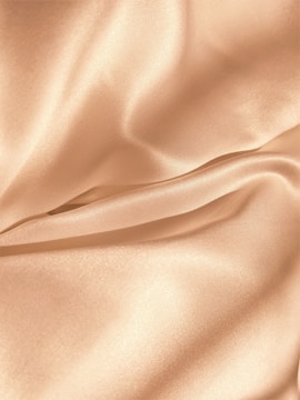 Close-up of delicate satin bonnet resting on soft fabric.
