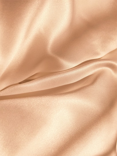 Close-up of a flowing champagne satin gown catching soft light, highlighting its smooth texture.