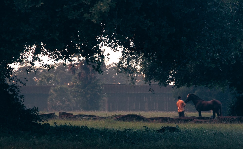 man in orange shirt sitting on green grass field during daytime