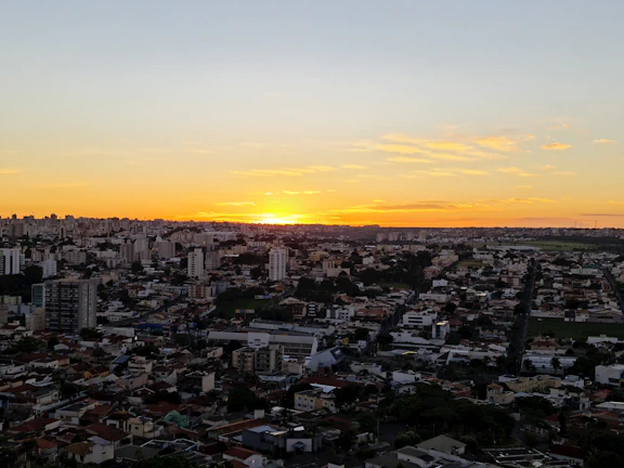 A vibrant sunset over a city skyline captured by drone, highlighting warm golden hues.