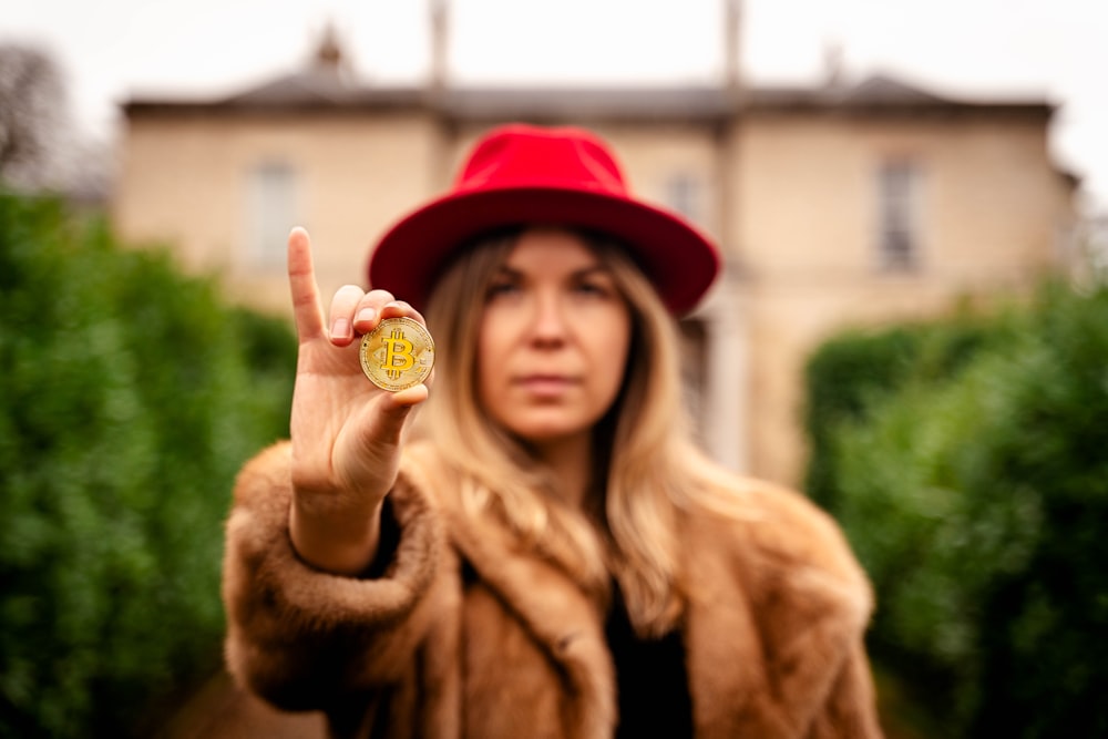 woman in brown fur coat holding yellow heart ornament